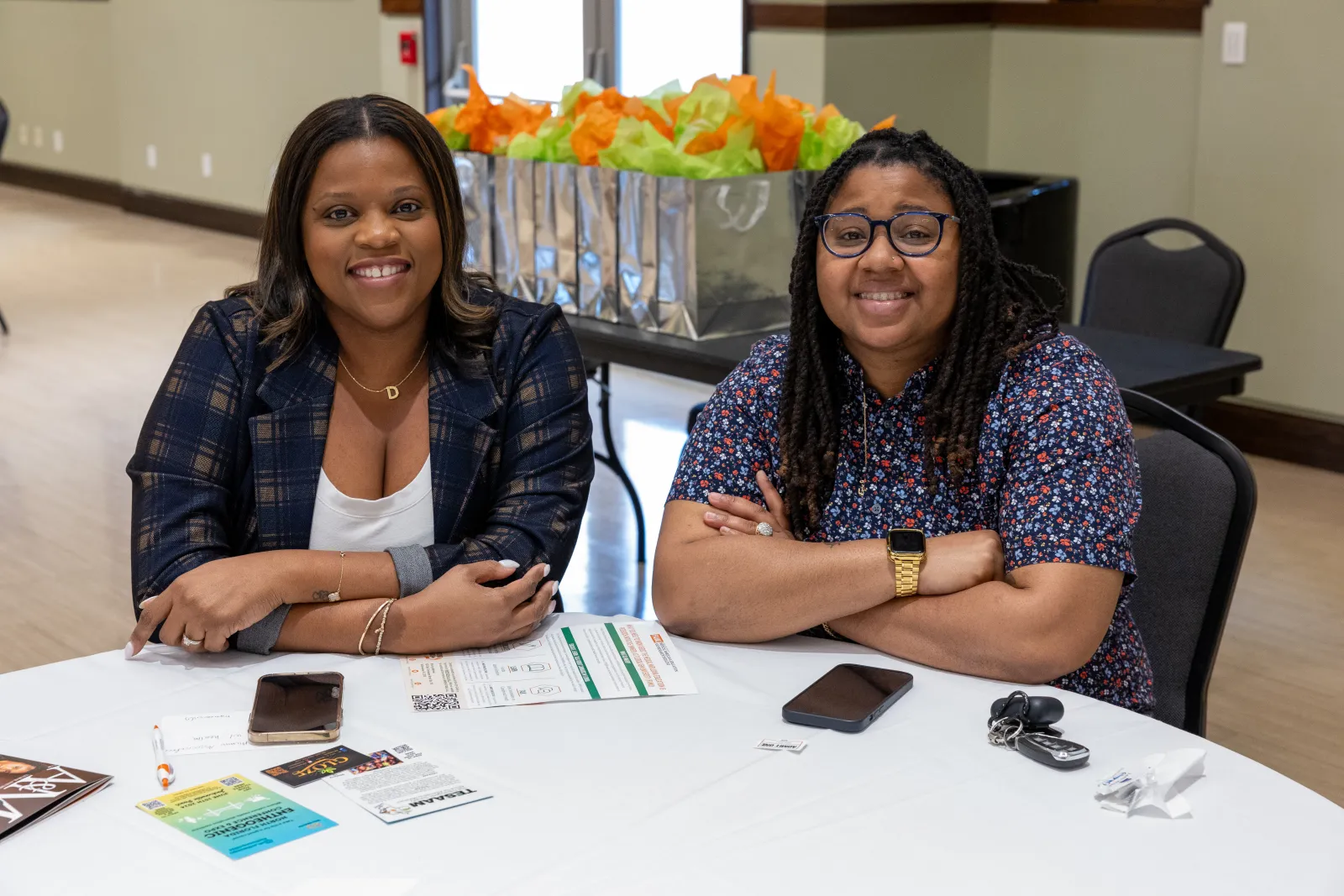 a couple of women sitting at a table with a card and a phone