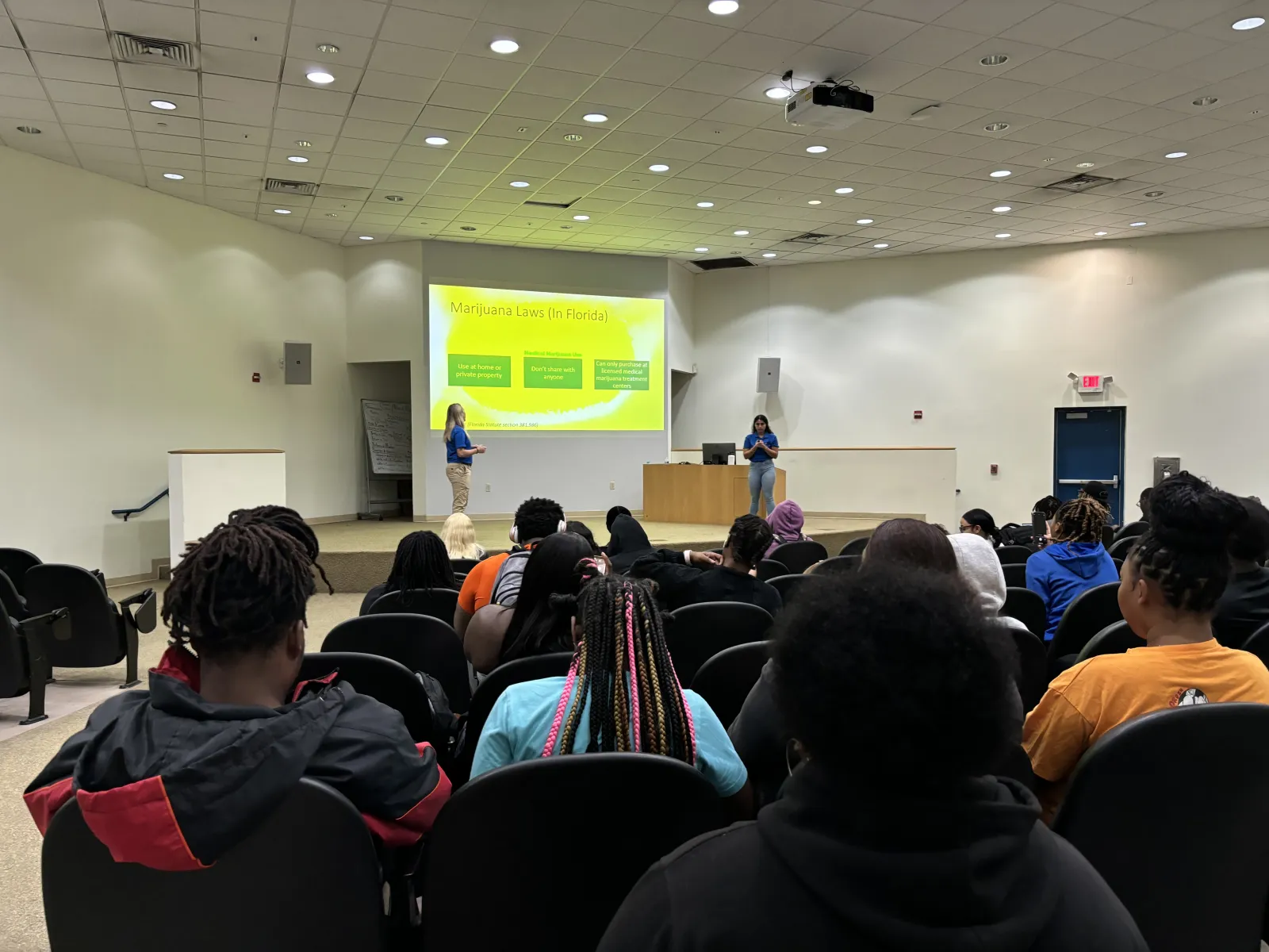 a group of people sitting in a room with a projection screen