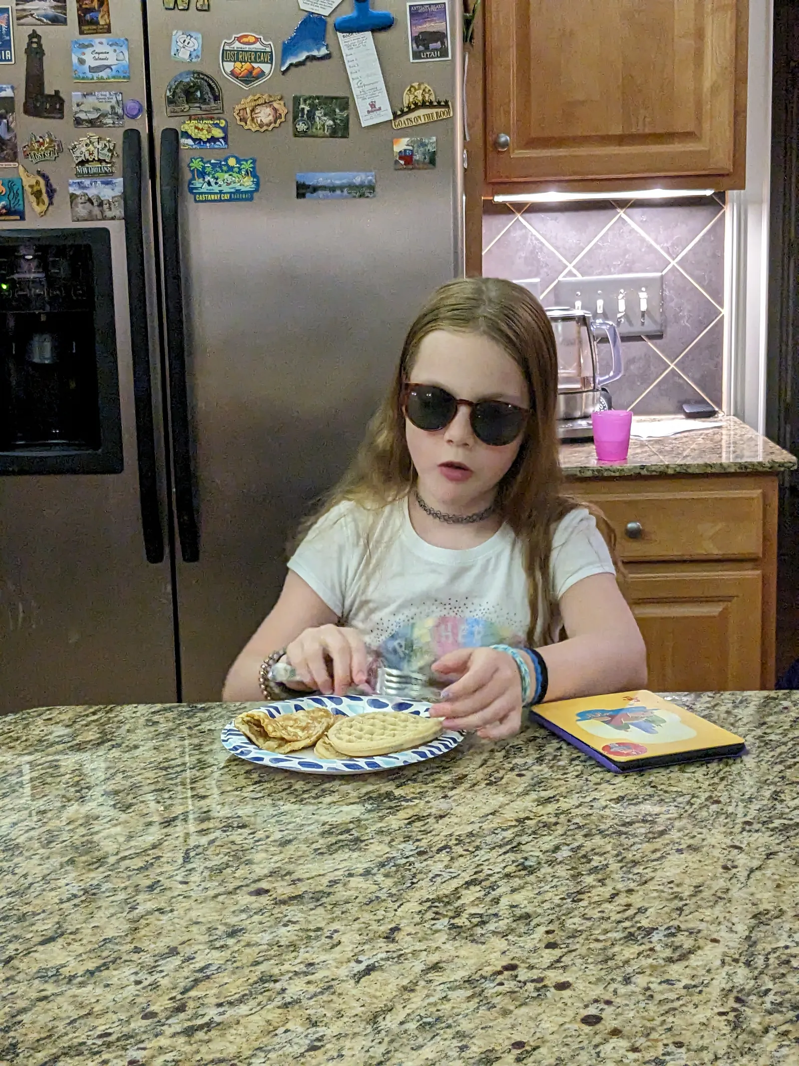 a girl sitting at a table with a plate of food