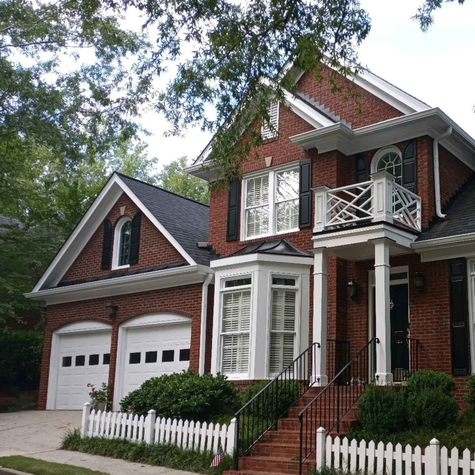 a large brick house with a white picket fence and a white picket fence