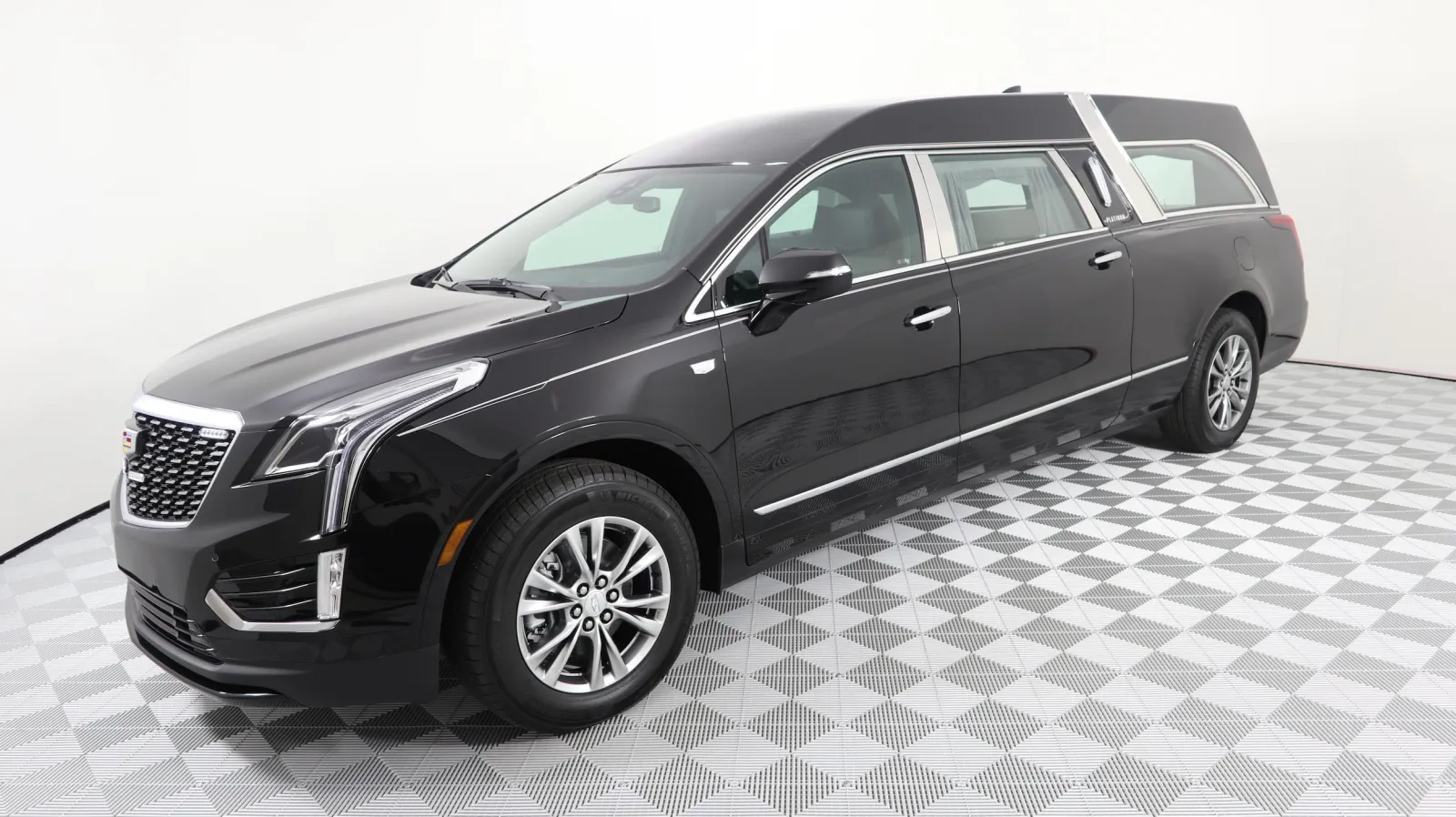 A sleek black Cadillac hearse showcased on a patterned floor in a studio setting.
