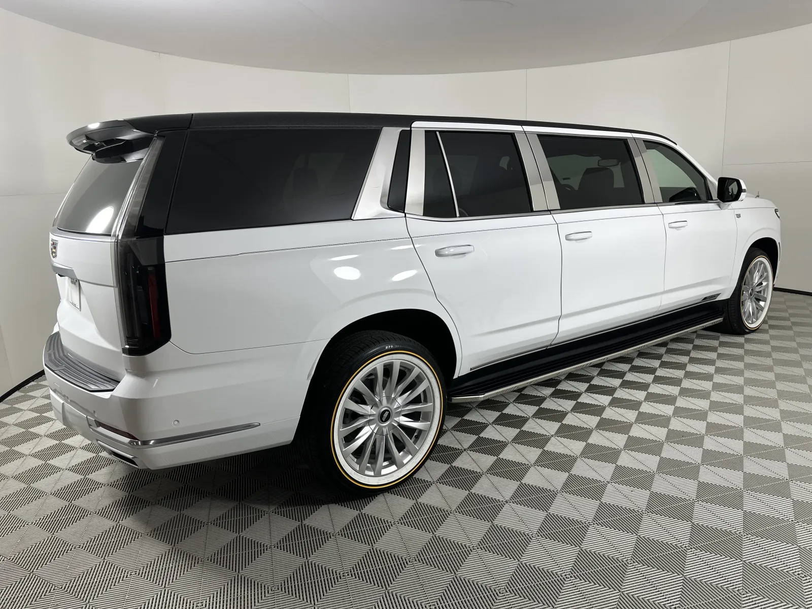 White luxury stretched SUV limousine with black tinted windows on checkered showroom floor
