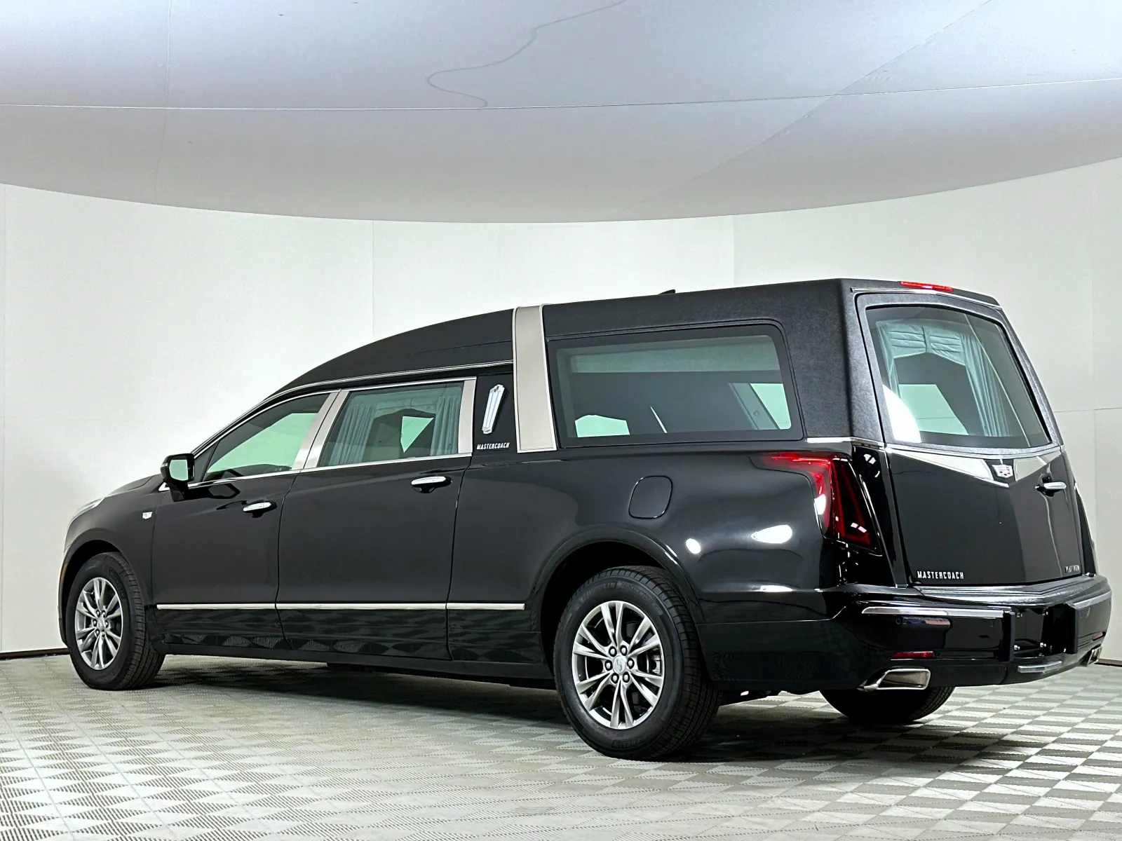 Black luxury Cadillac hearse with extended rear cargo area parked in white studio environment