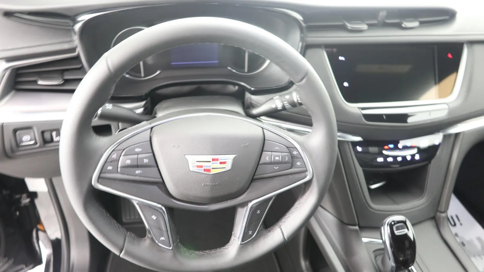 Close-up of a Cadillac steering wheel and dashboard with modern controls and sleek design.
