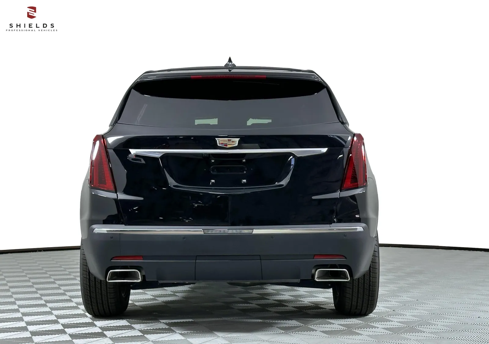 Rear view of a black Cadillac SUV on a checkered floor backdrop, showcasing its sleek design and modern features.