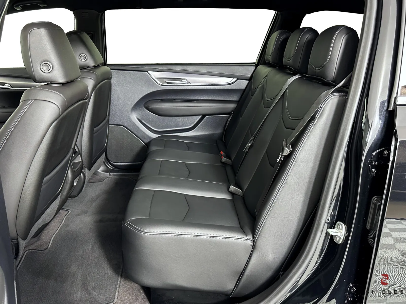 Interior view of a spacious black leather car backseat with three passenger seats.