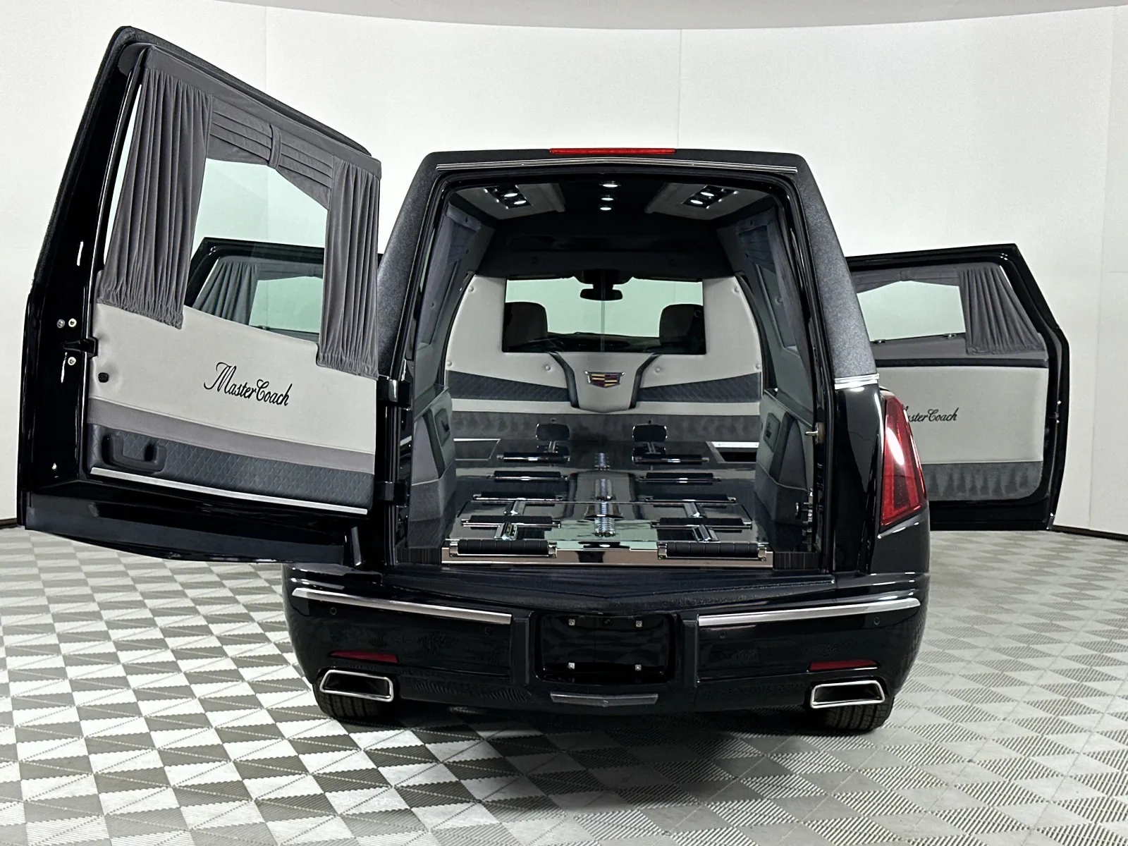 Rear view of a black MasterCoach hearse with open doors revealing interior coffin holders and luxury detailing.