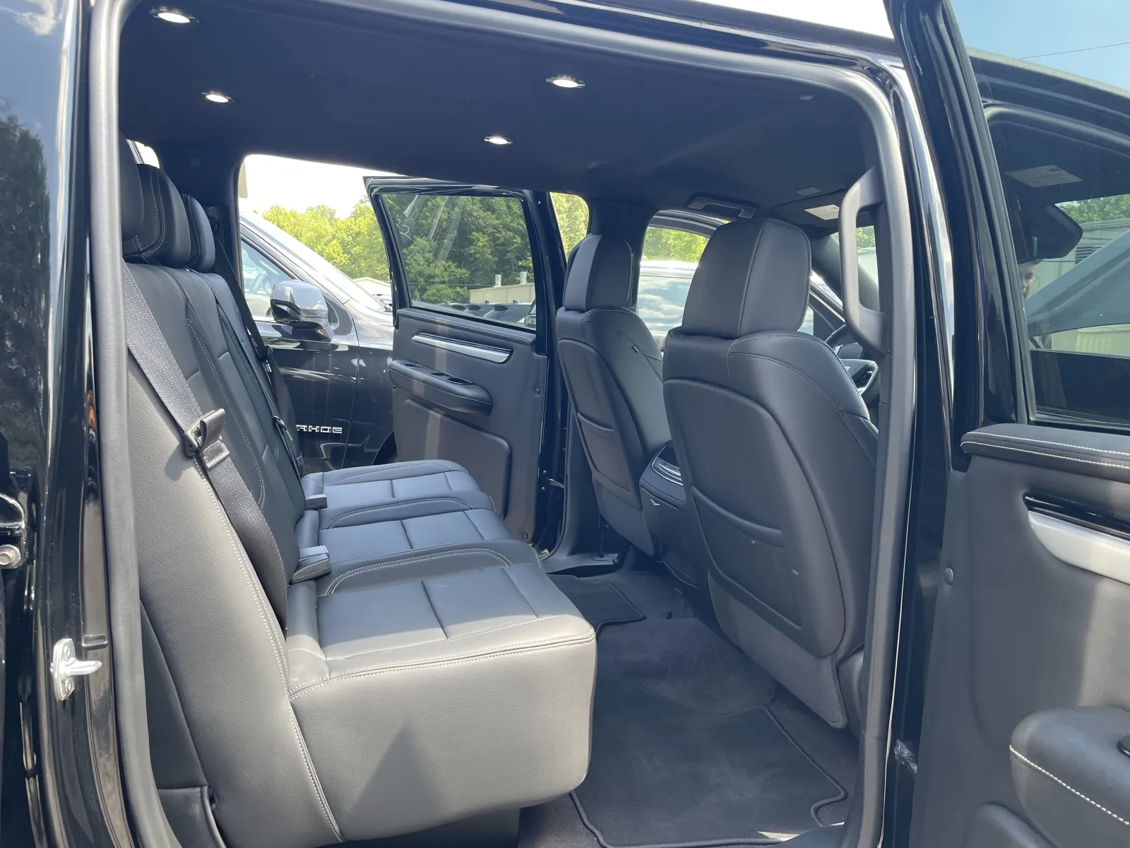 Spacious rear seats of a black pickup truck with leather upholstery and open rear doors.