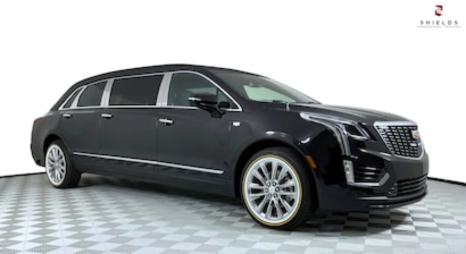 Sleek black Cadillac crossover SUV with premium wheels and elegant design on a checkered floor.