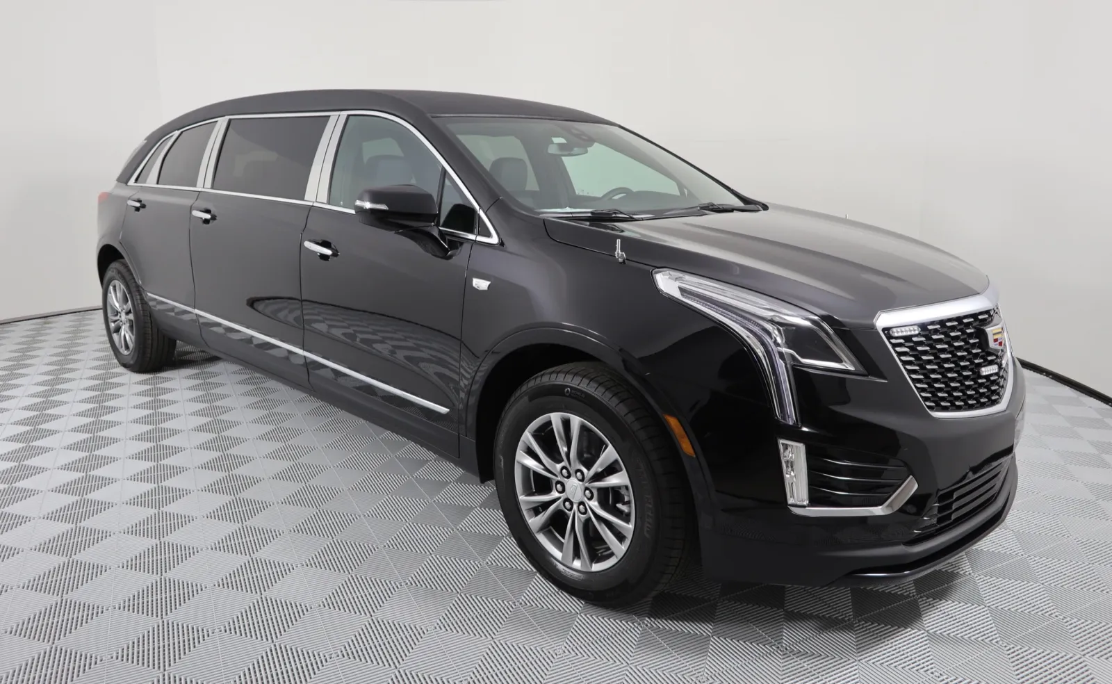 Sleek black Cadillac SUV with elegant lines, showcased on a patterned floor backdrop.