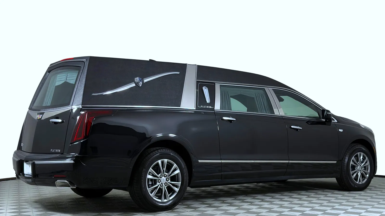 Black luxury Cadillac hearse with chrome accents on a checkered floor against white background