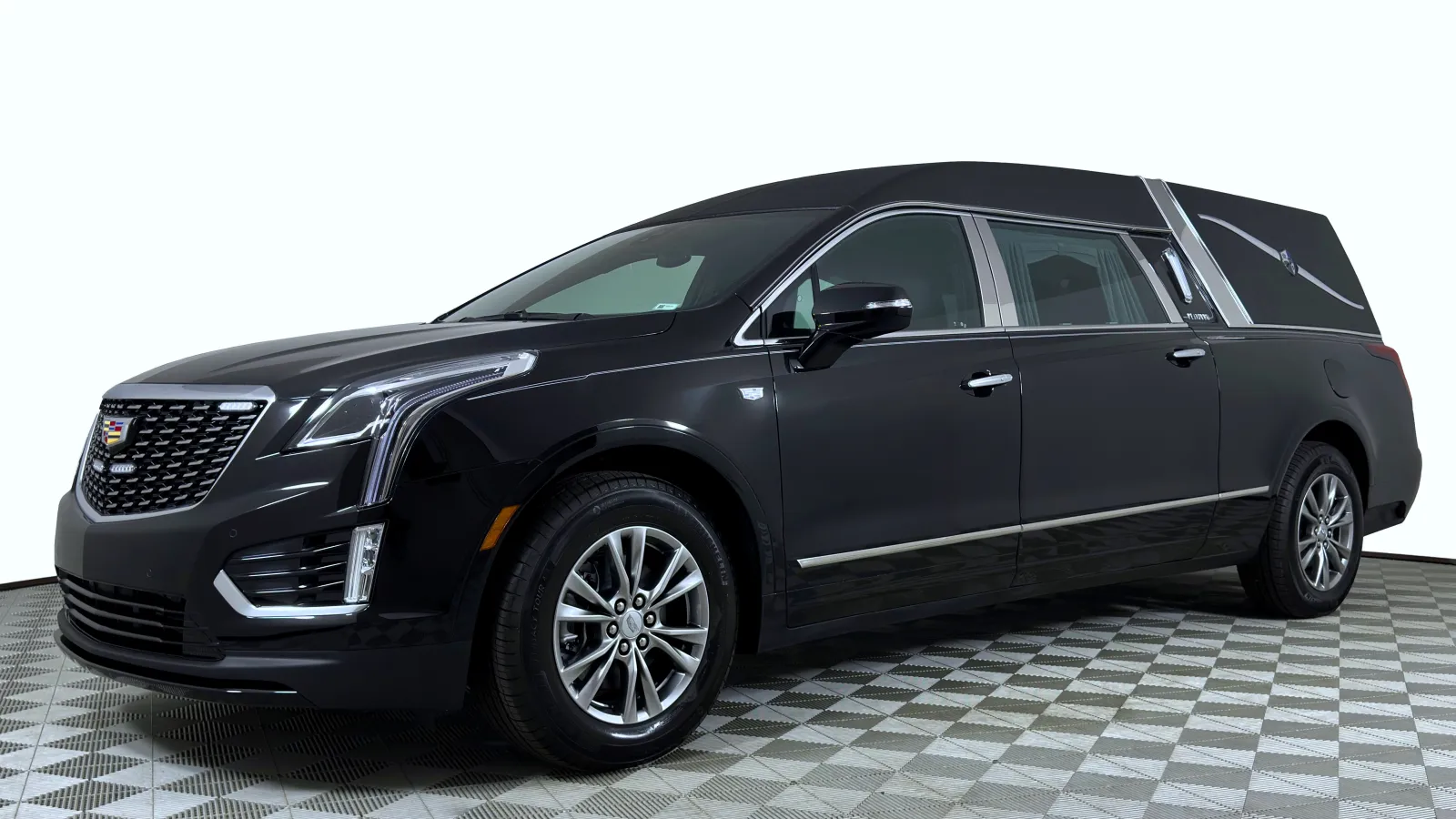 Black Cadillac hearse with chrome details parked on checkered floor under white lighting.