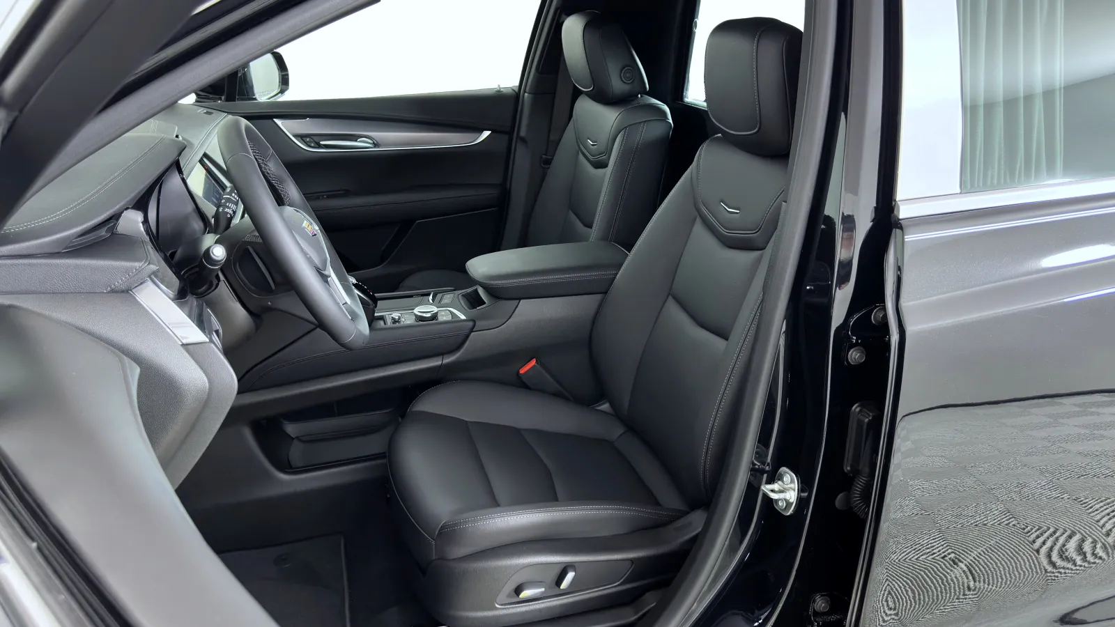 Interior view of a modern black car showing leather front seats and dashboard with steering wheel.