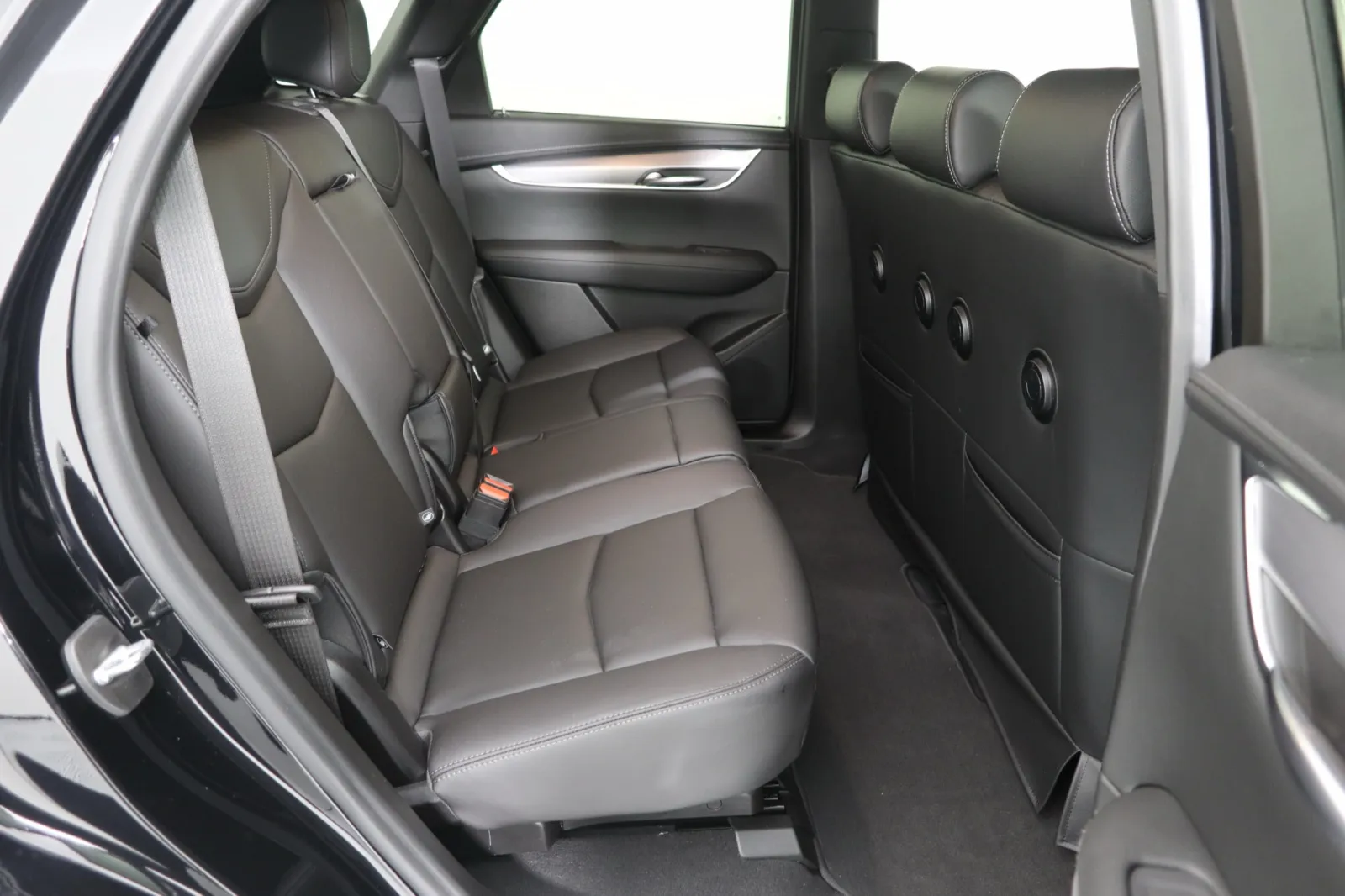 Interior view of a luxury SUV's rear seating area with black leather upholstery.