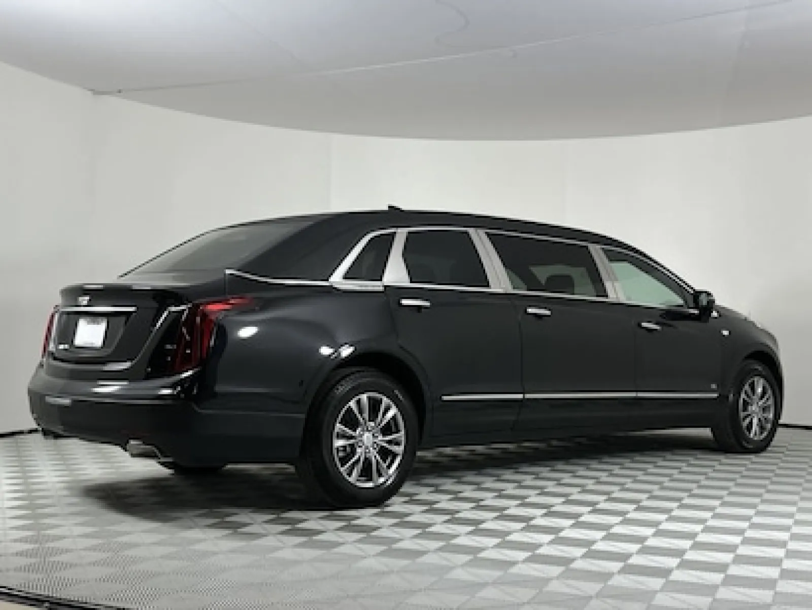 Sleek black Cadillac limousine parked in a modern studio with illuminated background.