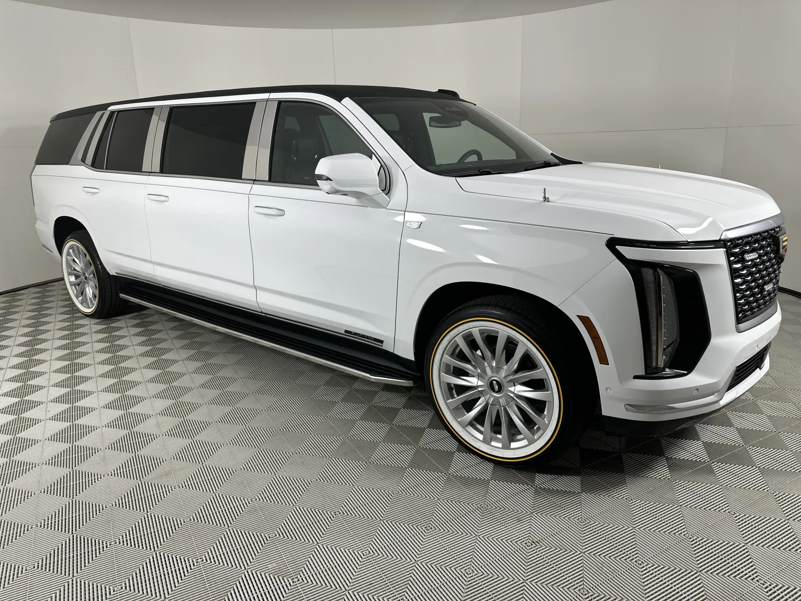 White luxury extended SUV limousine with sleek design and tinted windows in showroom with patterned floor.