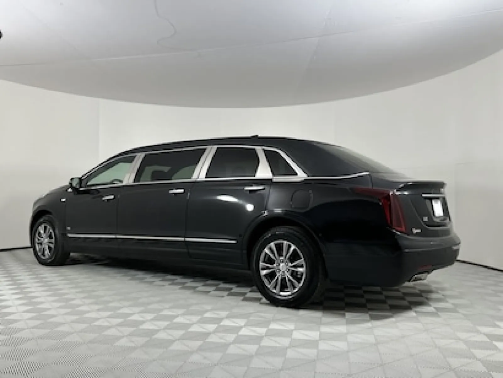 A sleek black luxury limousine parked in a clean, well-lit studio space.