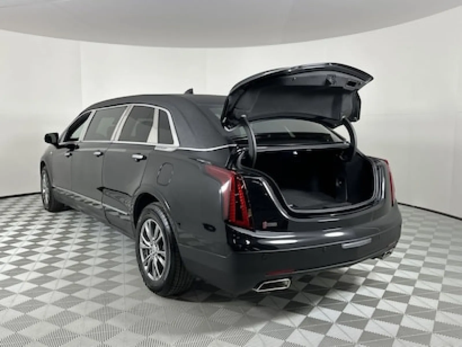 Rear view of a black luxury limousine with an open trunk showcasing ample storage space.