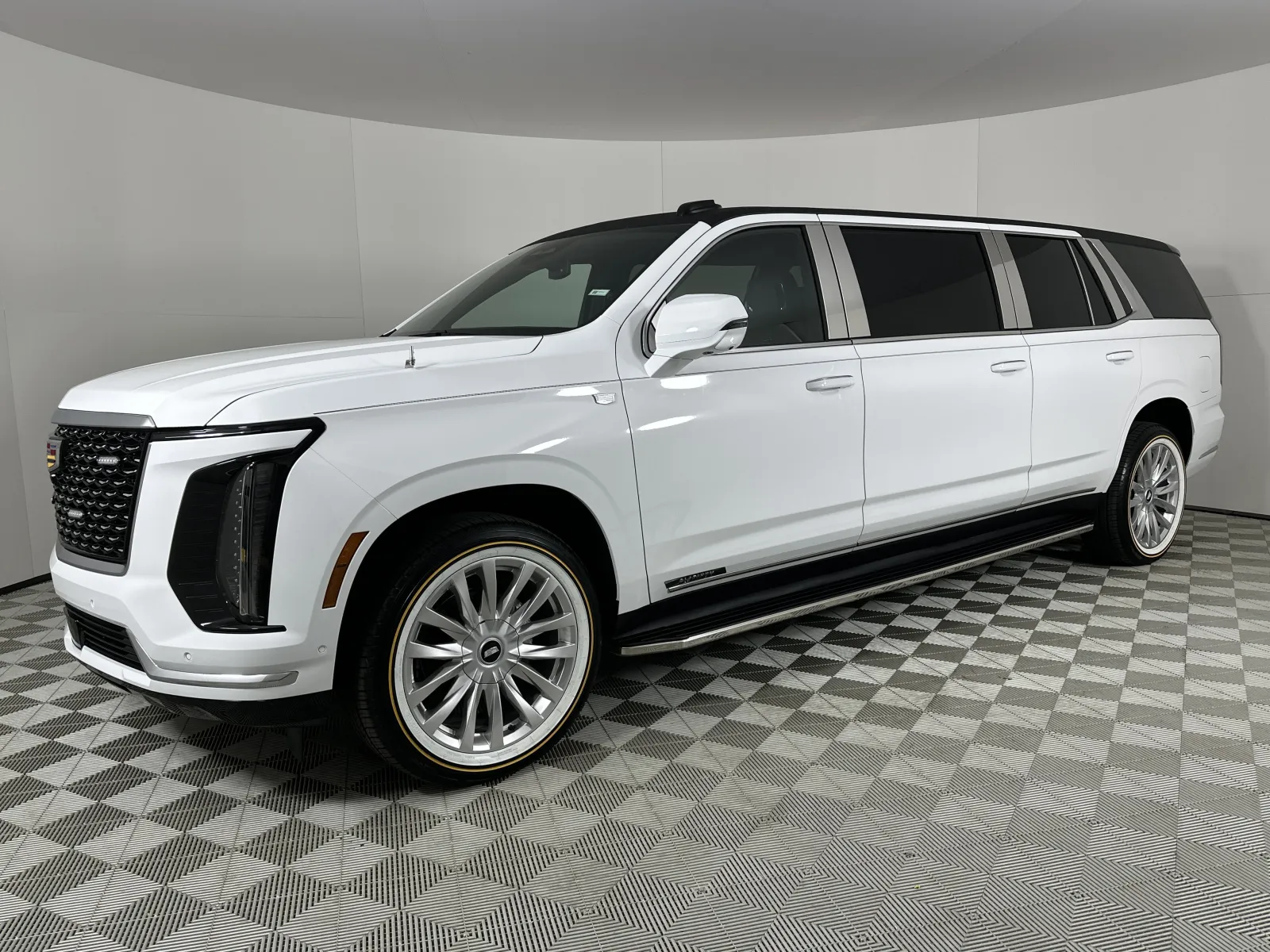 White extended luxury SUV limousine with modern design, large wheels, and tinted windows parked on checkered floor.