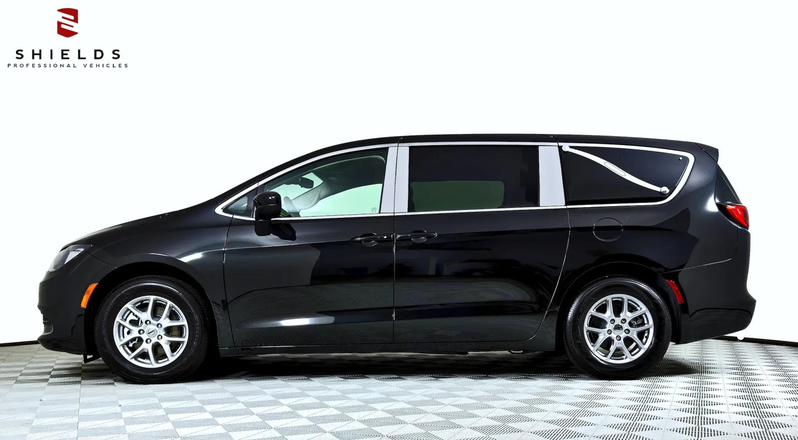 Side view of a sleek black minivan with shiny wheels against a white background.