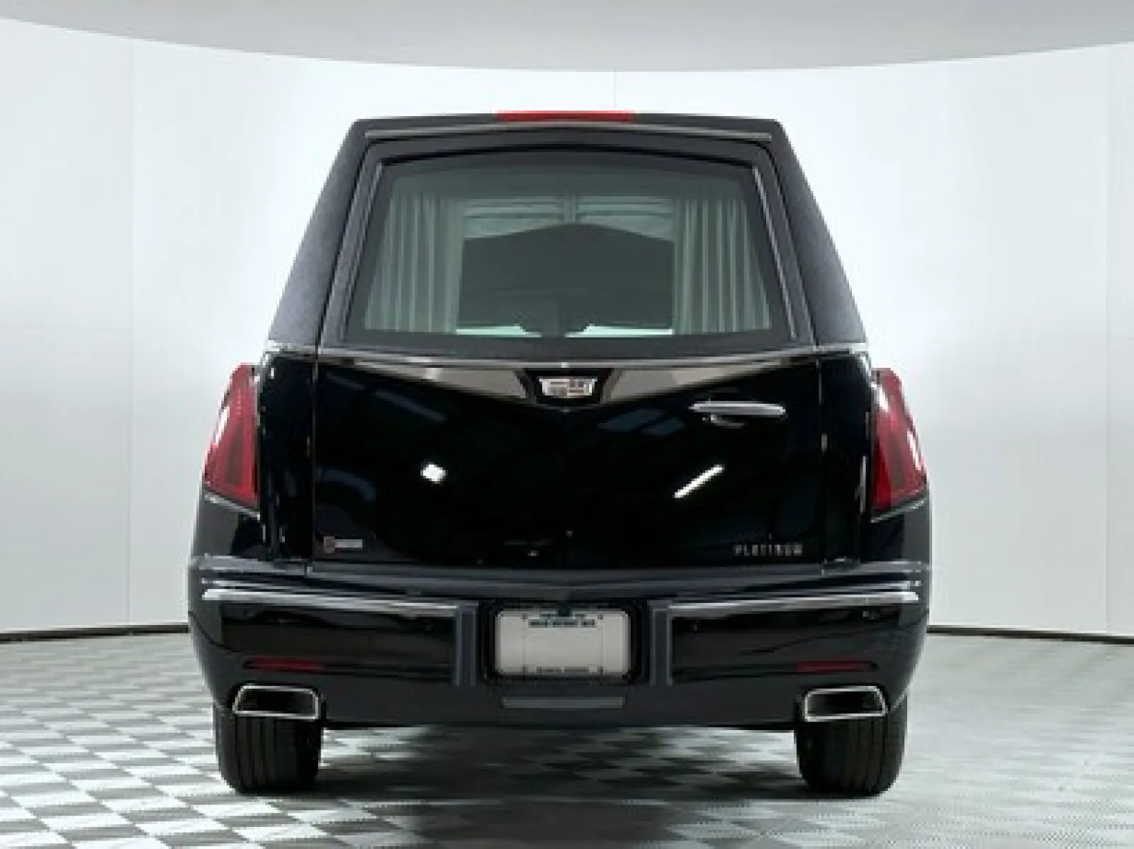 Black luxury hearse with sleek design and prominent rear features in a studio setting.