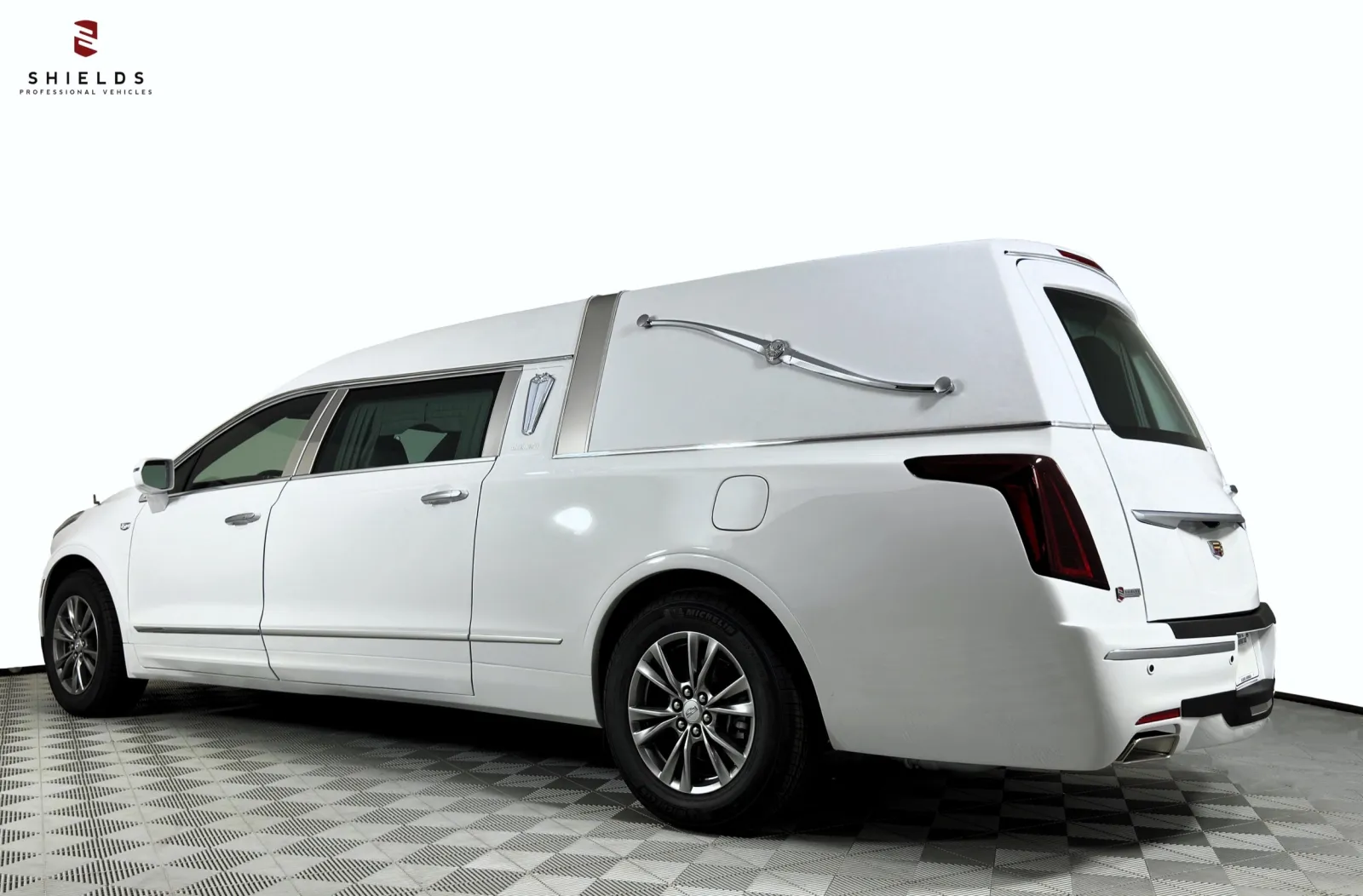 White funeral hearse with sleek design, viewed from the side against a plain background.
