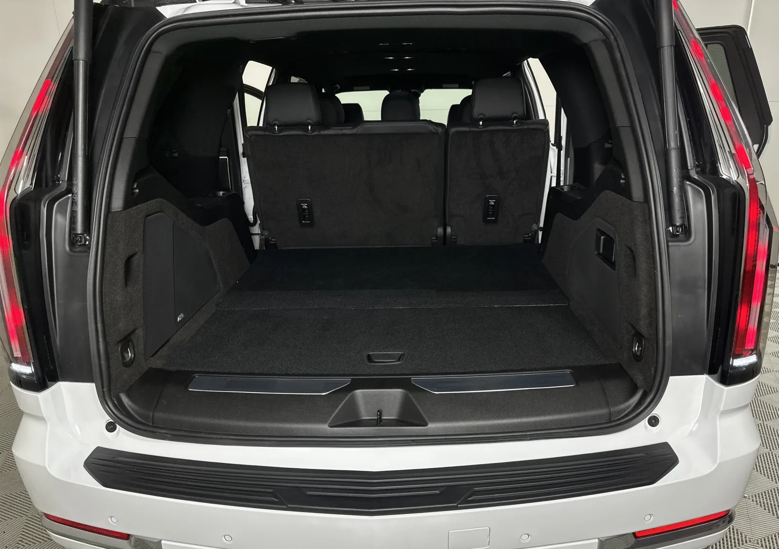 Open trunk of a white SUV showing spacious cargo area with black interior and rear seats upright