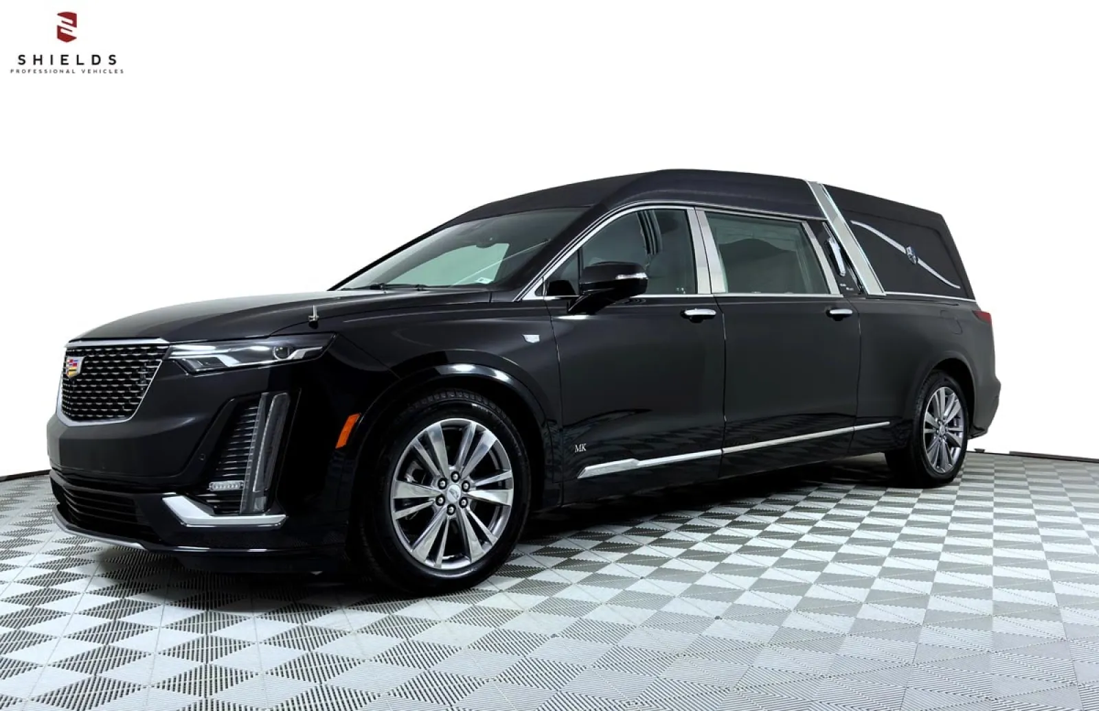 Luxury black Cadillac funeral hearse with sleek design and chrome accents on a checkered floor.