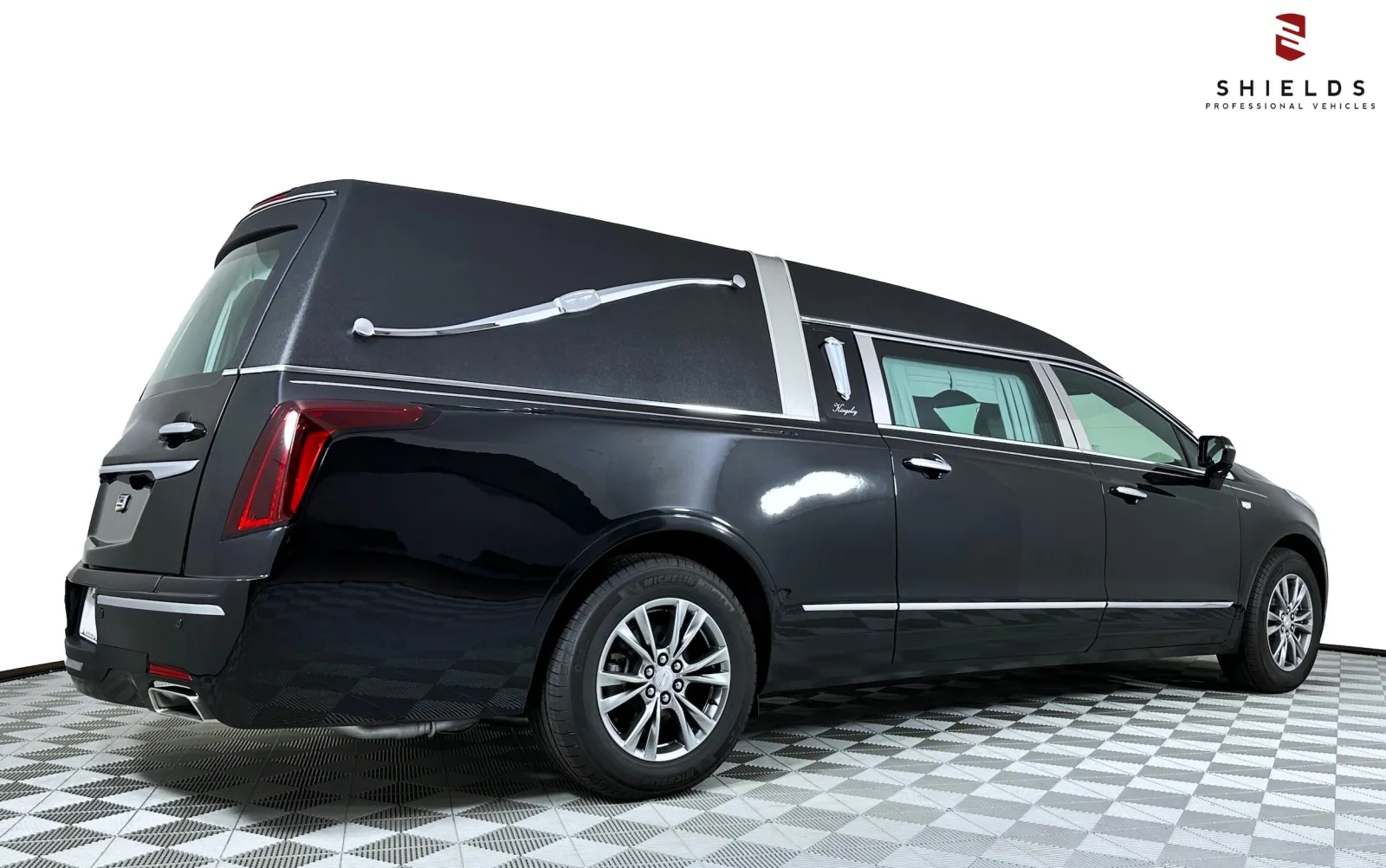 Black hearse with sleek design and modern features, showcased on a patterned floor.
