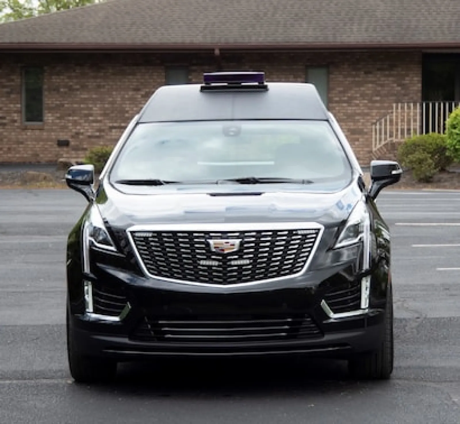 Front view of a sleek black Cadillac SUV parked outside a building.