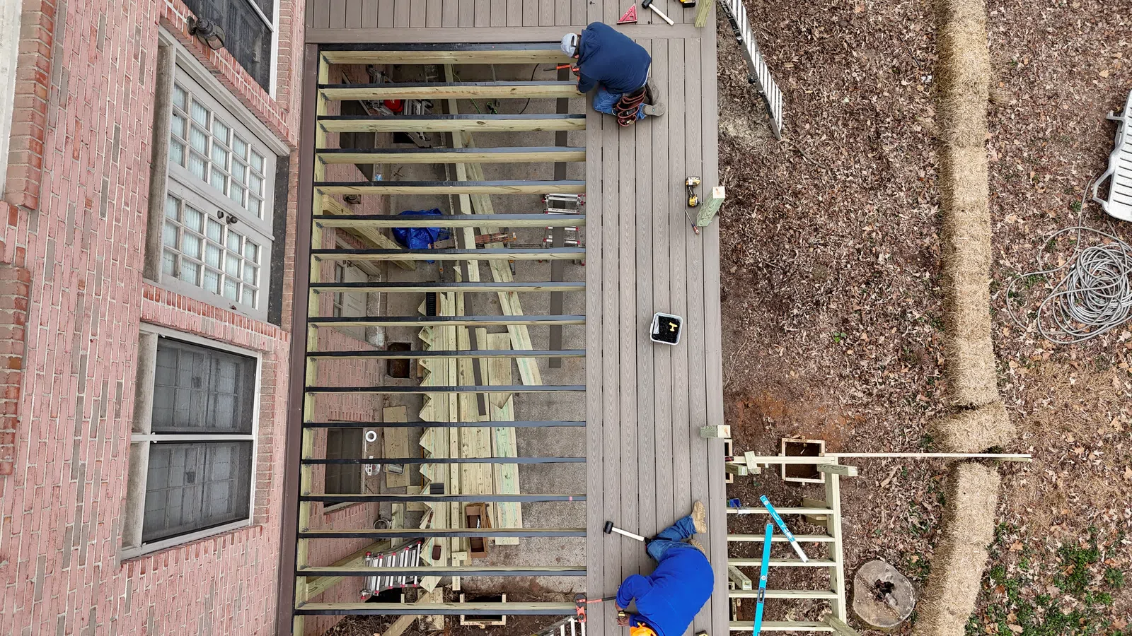 An aerial drone view looking down on contractors installing composite deck boards over a sturdy wood joist framework, completed by Atlanta deck builders in Marietta by Nelson Exteriors.