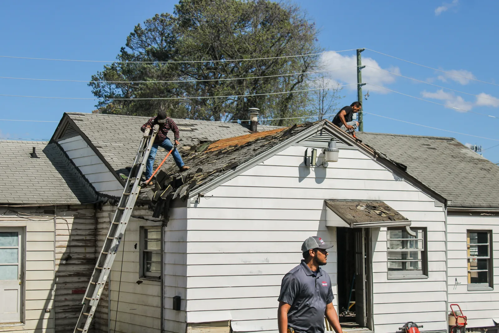 Nelson Exteriors crew repairing roof shingles on a white siding home, project by Nelson Exteriors in Marietta.