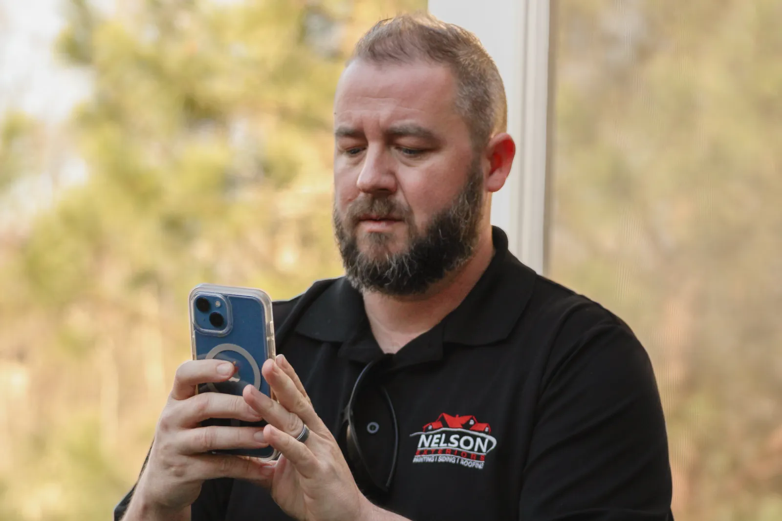 A Nelson Exterior employee holding a phone, taking a photo and notes in Marietta
