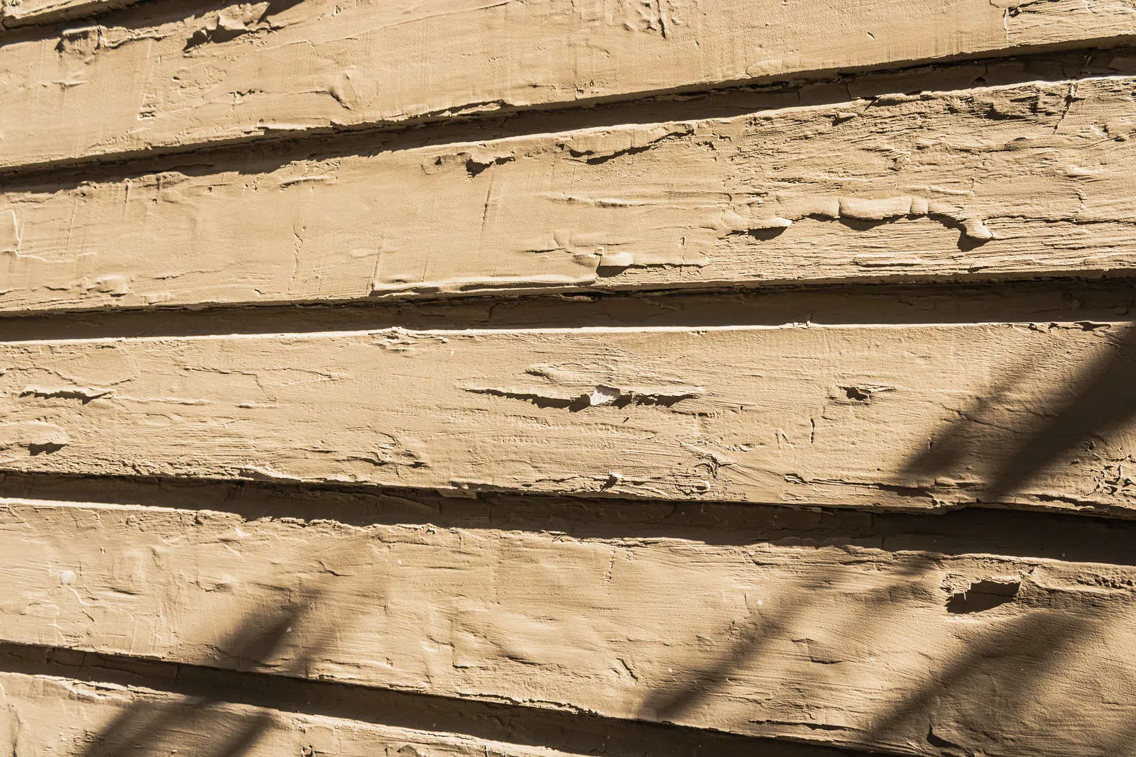 Close-up of peeling paint and warped wooden house siding caused by severe Marietta GA humidity damage exterior siding repair in Marietta by Nelson Exteriors.