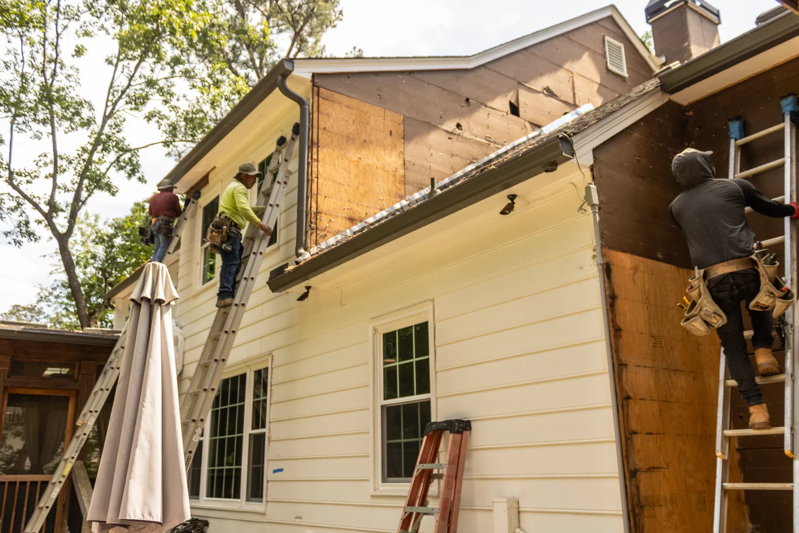 Contractors on extension ladders removing rotted exterior wall panels suffering from Marietta GA humidity damage siding replacement services in Marietta by Nelson Exteriors.