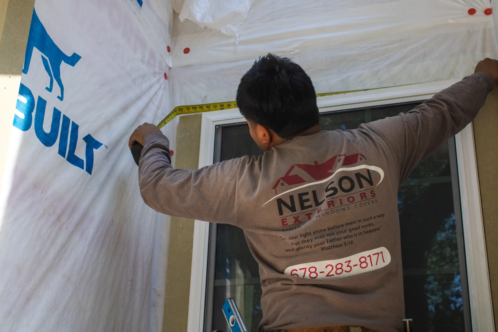 Contractor measuring window installation area during exterior renovation time and materials vs cost plus contract project in Marietta by Nelson Exteriors