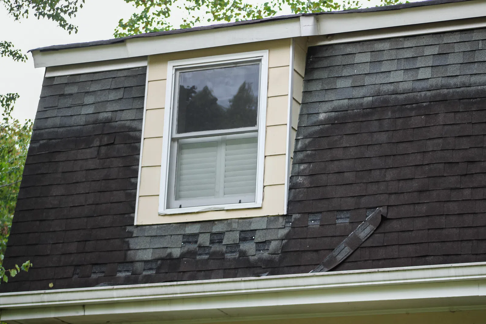 A close-up of aging roof shingles near a dormer, supporting workmanship vs manufacturer roof warranty in Marietta by Nelson Exteriors.