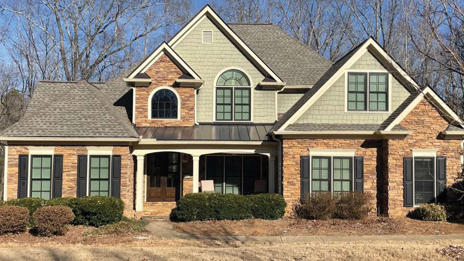 Stone and siding home with bronze Infinity from Marvin windows.