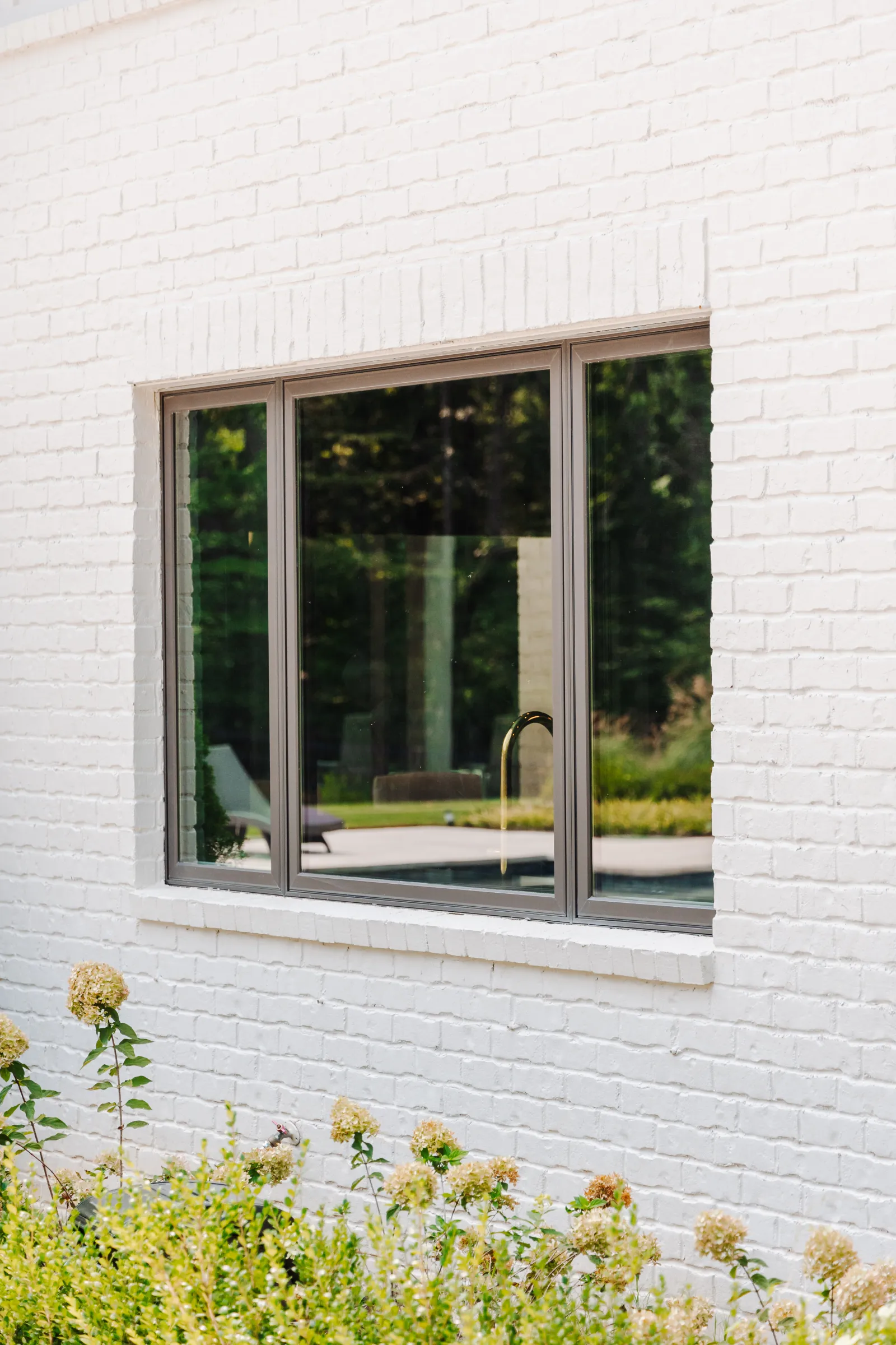 Bronze casement windows installed in white brick house's kitchen 