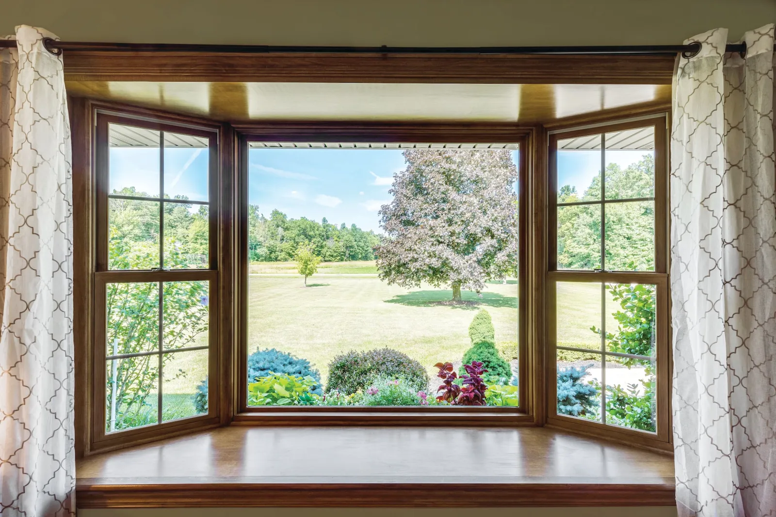 Custom fiberglass bay window unit with double hung windows overlooking a vibrant Middle Tennessee garden, showcasing high-end home exterior views in Nashville.