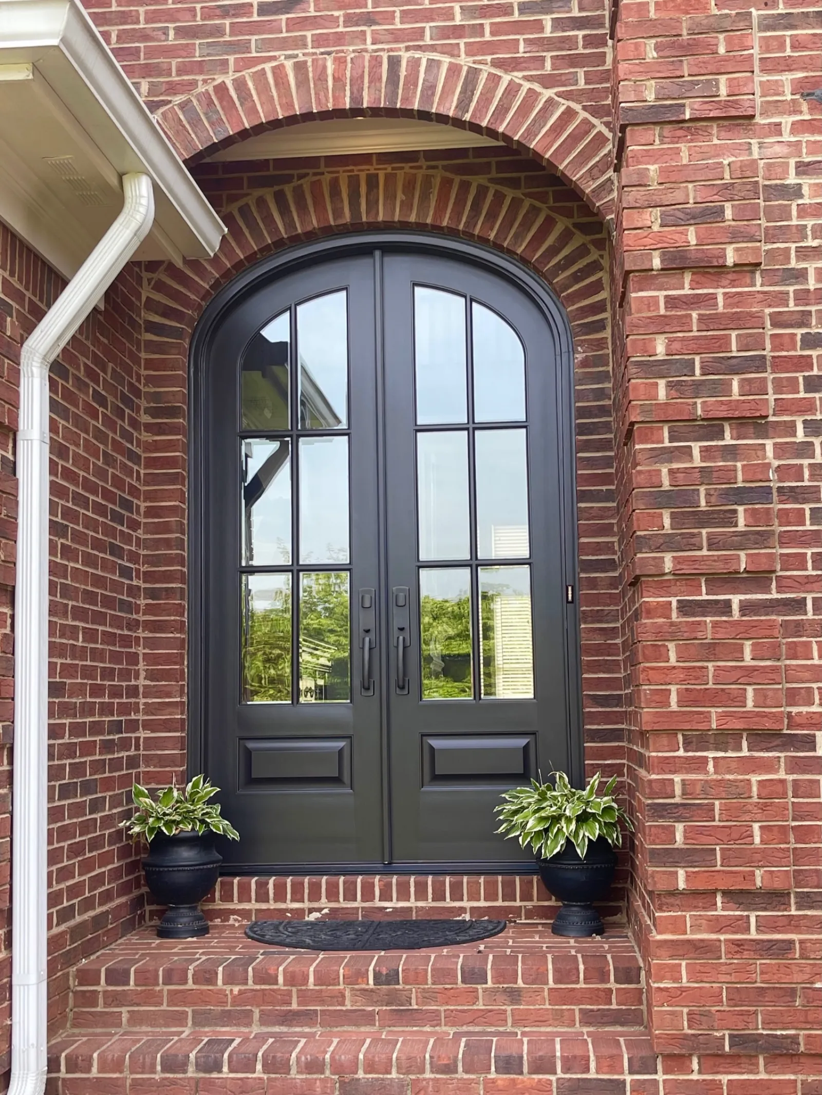 Brick house with black arched double entry doors from North Georgia Replacement Windows