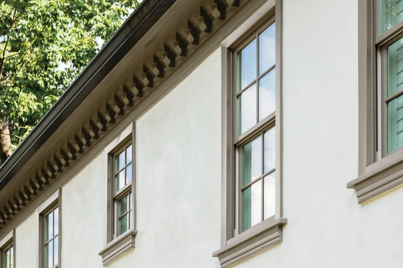 Close-up of custom double hung windows on a beige exterior, highlighting high-quality residential window replacement.