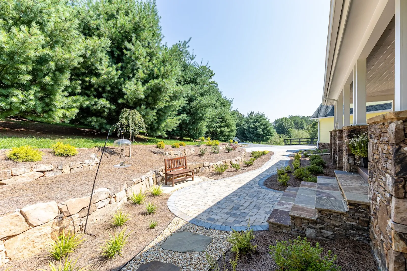 a small patio with a bench and a brick path