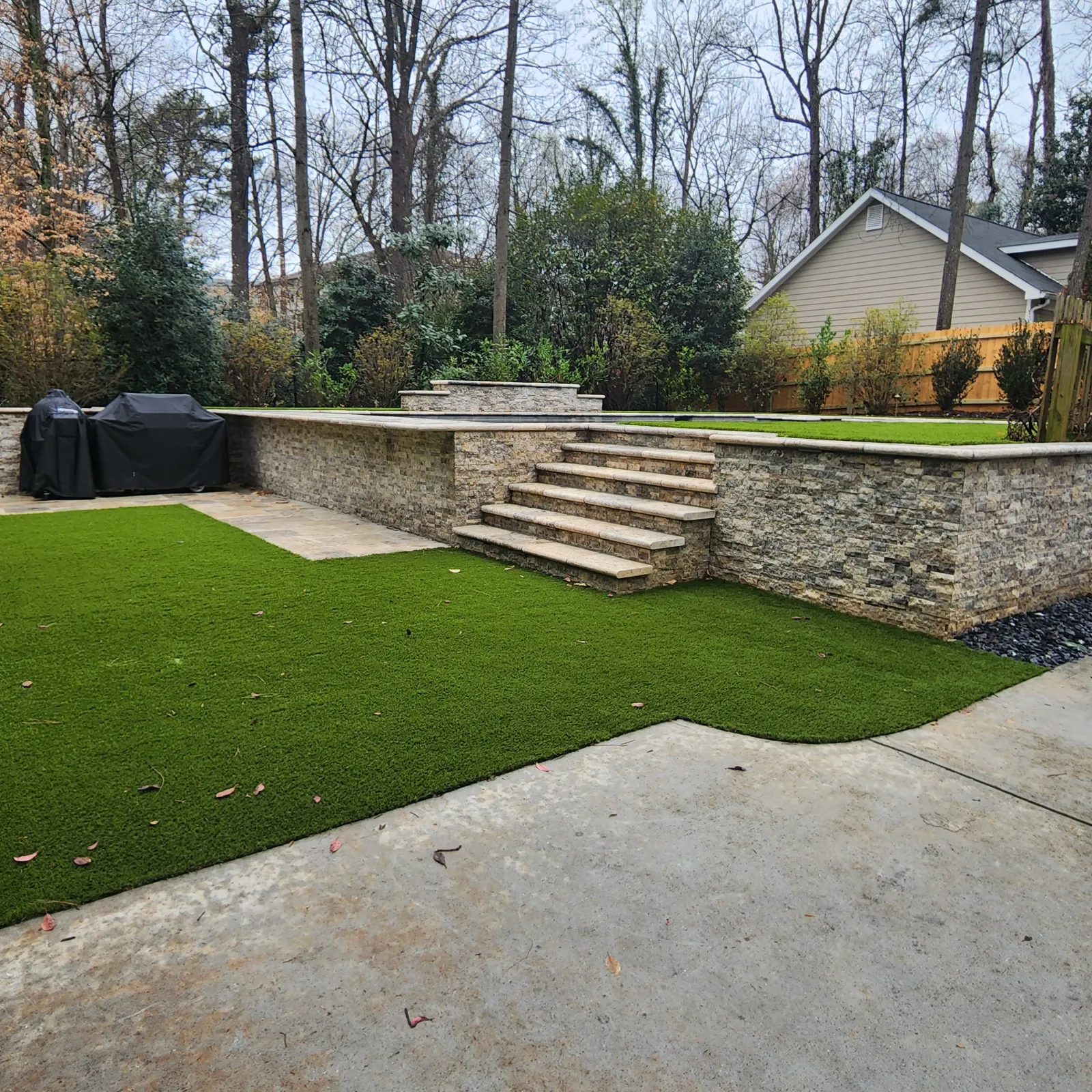 a stone wall with a grass lawn