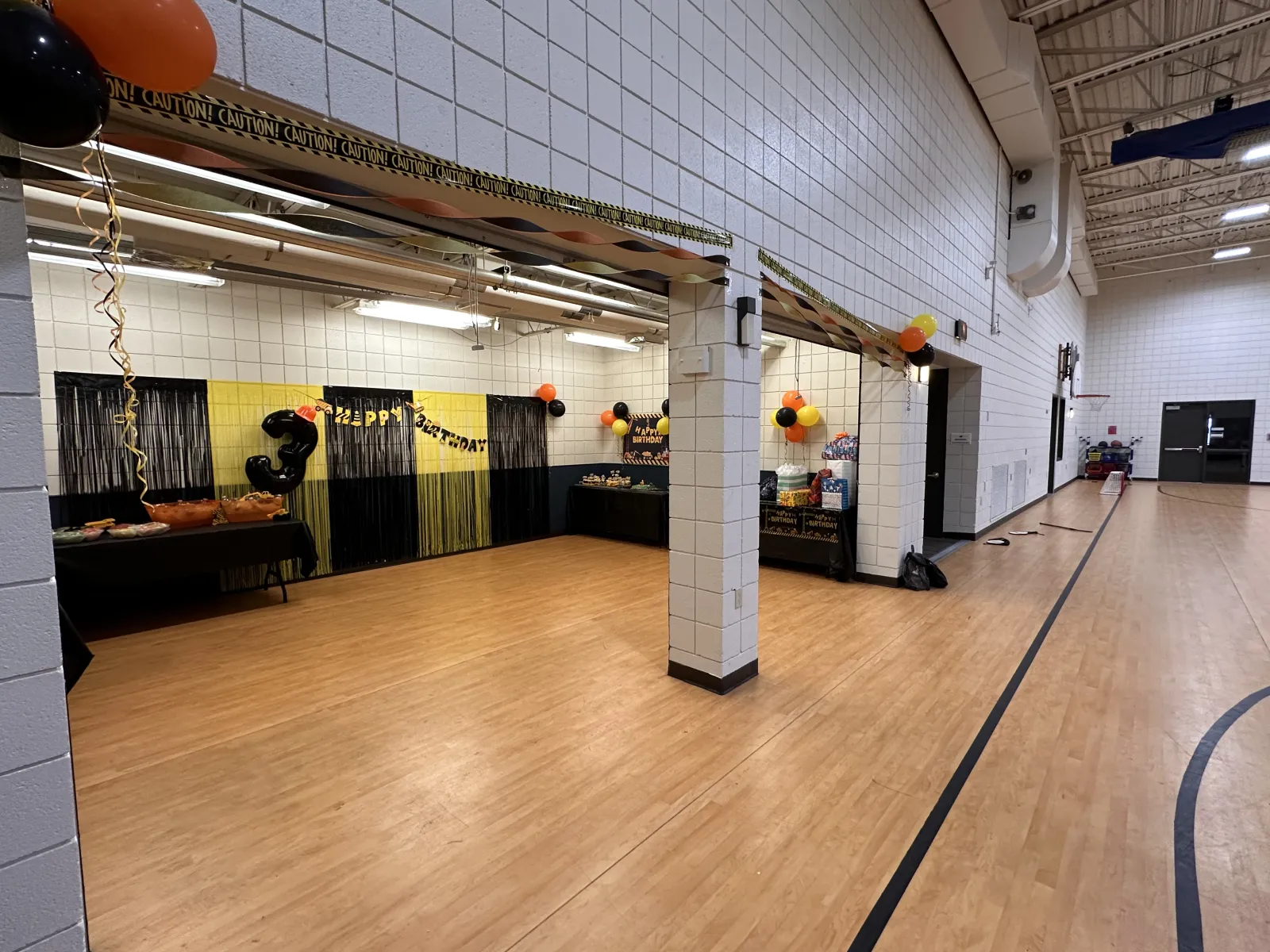 Wide view of a decorated event space with balloons and tables set for a celebration.
