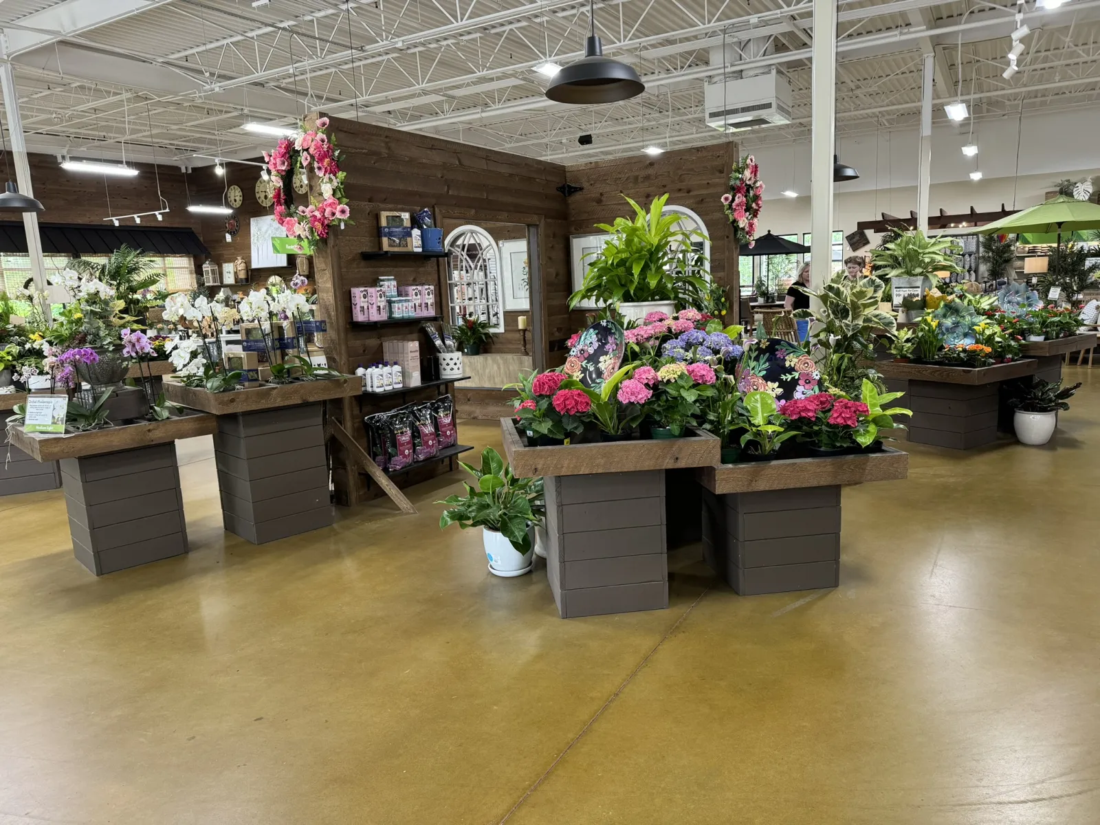 Indoor garden center with wooden planters displaying colorful flowers and green plants under bright lighting.