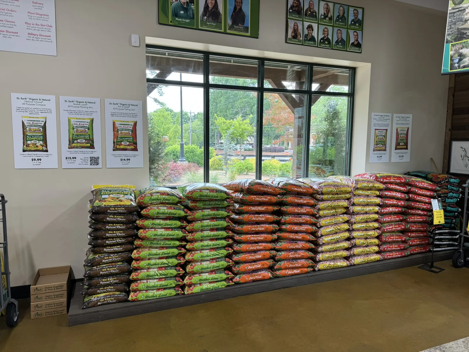 Stacks of colorful Dr. Earth's organic gardening soil bags displayed indoors near large windows in a nursery.
