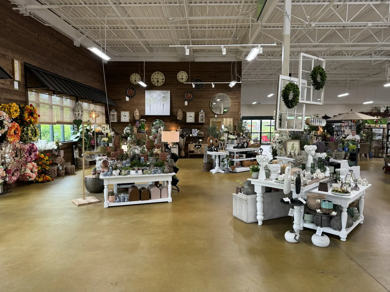 Interior view of a rustic gift shop with floral arrangements, decorative clocks, and home decor items on display.