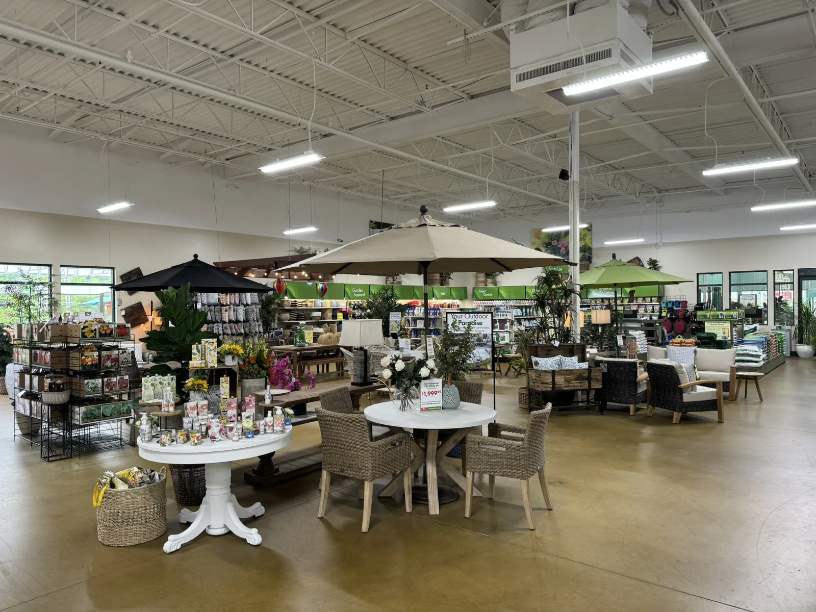 Indoor garden center with patio furniture, umbrellas, plants, and garden supplies on display under bright lighting.