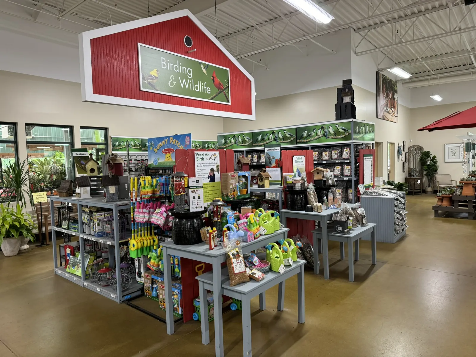 Indoor garden center section with birding and wildlife supplies, bird feeders, seed bags, and gardening tools.